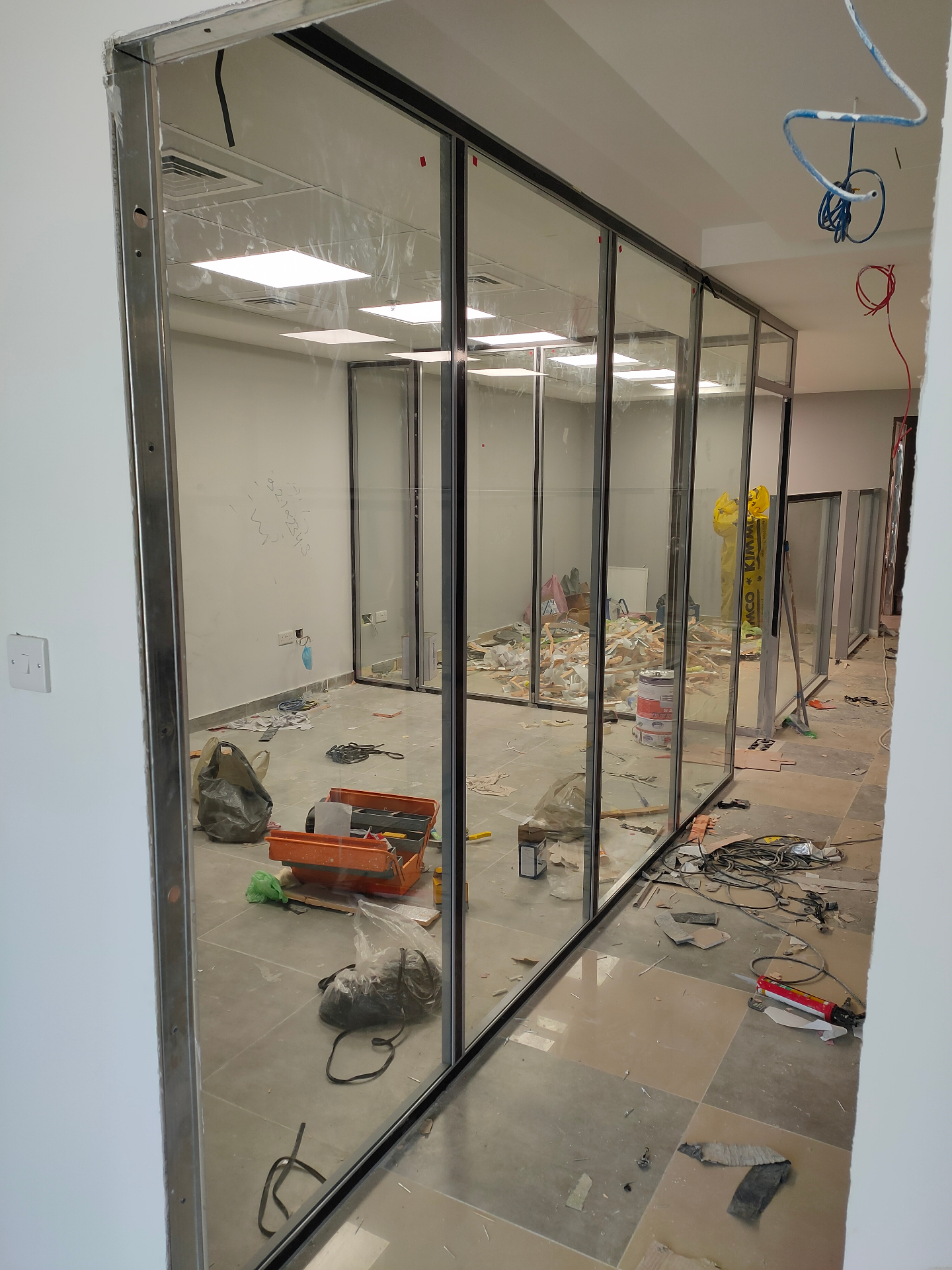 Acoustic glass partition installation Dubai — full-height frameless cabin with sound-rated door